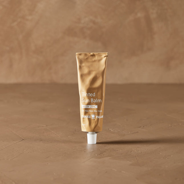 Thrive Tallow Tube of Tinted Sun Balm on a brown textured background