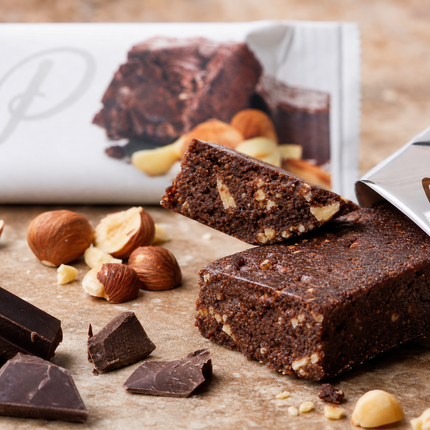 Close-up of Fibre Boost Choc Hazelnut protein bar texture with hazelnuts and dark chocolate